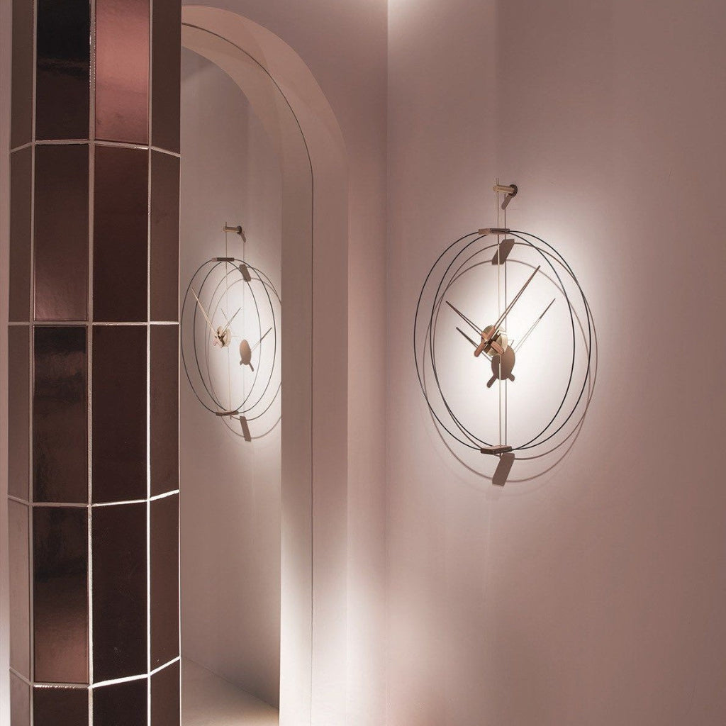 Decorative wall clock with a modern design on a light pink wall.