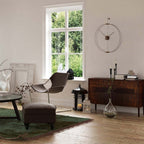 Living room with a large window, brown chair, and wooden sideboard.