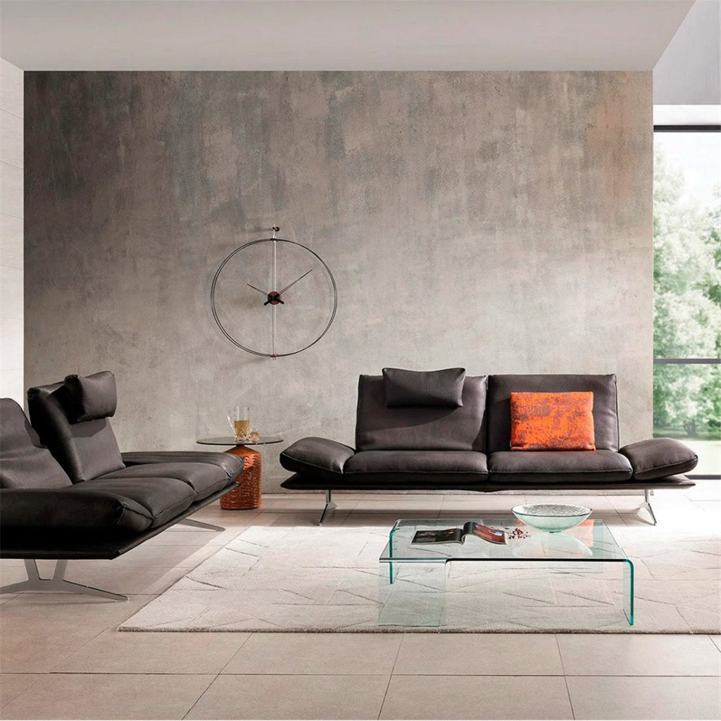 Modern living room with gray sofa, glass coffee table, and decorative wall clock.