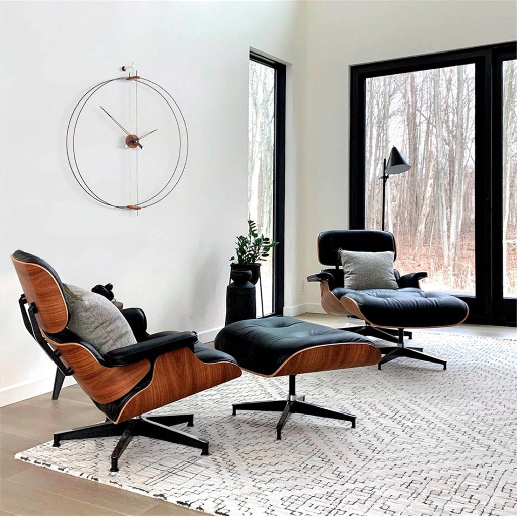 Modern lounge chair and ottoman in a stylish living room with large windows.