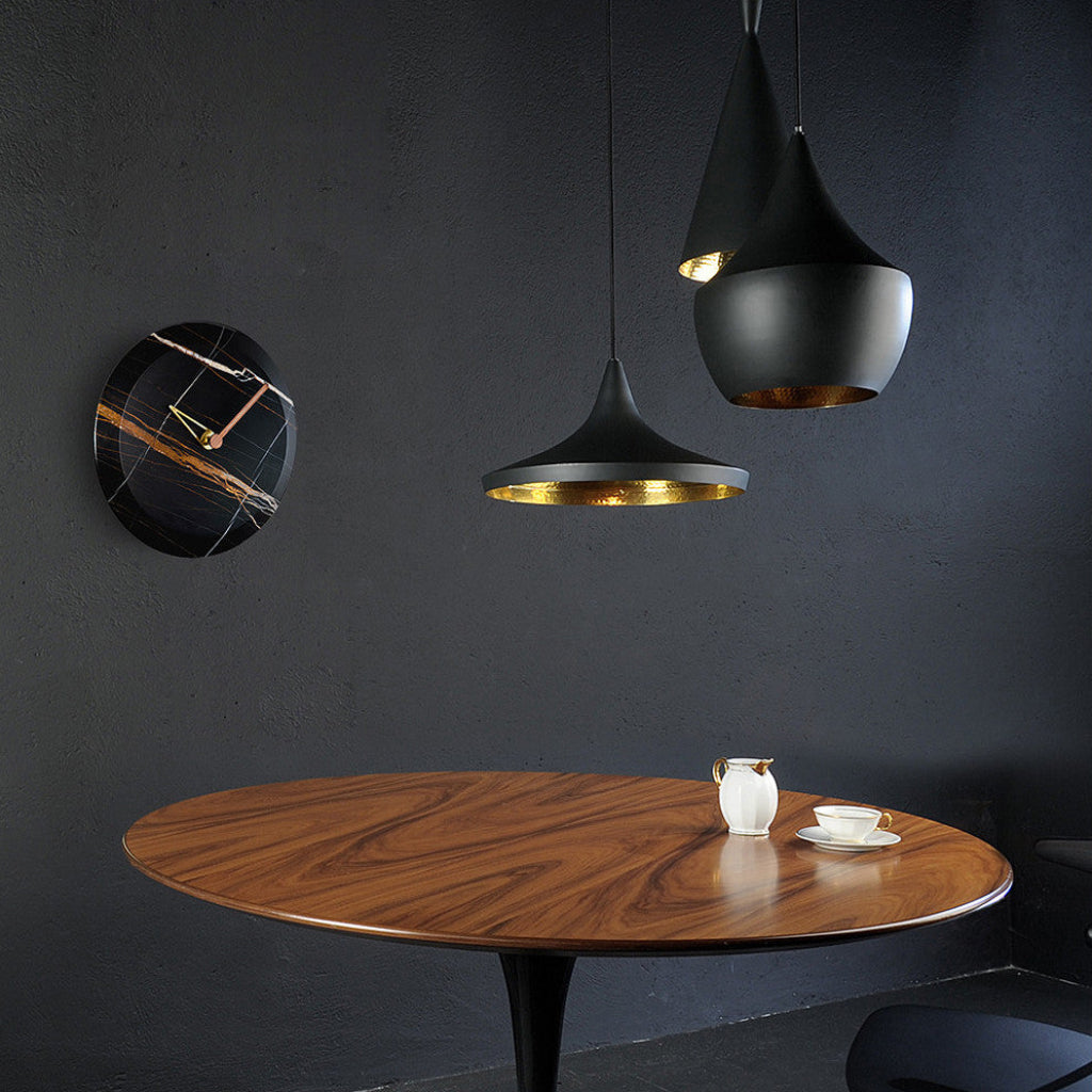Wooden table with decorative items against a dark wall with pendant lights.