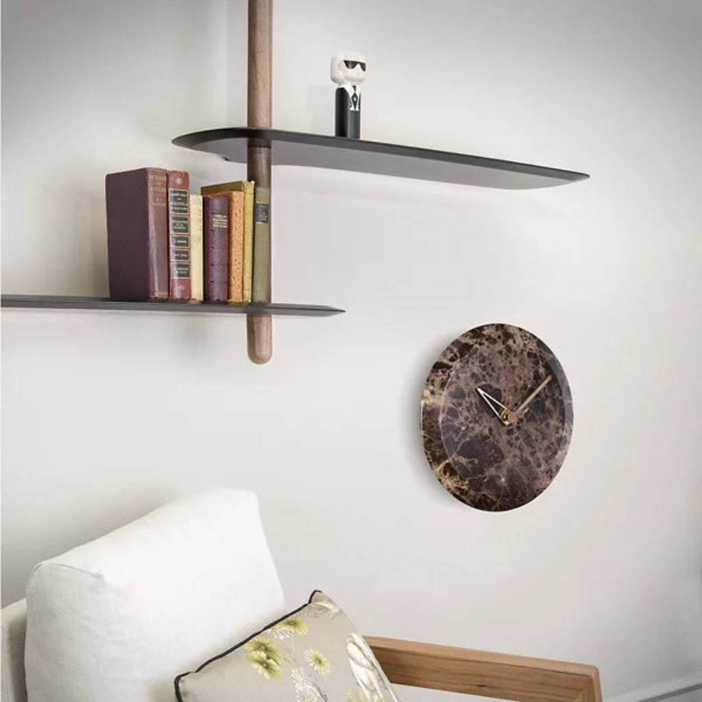 Wall clock on a white wall with shelves and books in the background