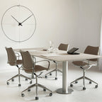 Modern office setting with a conference table and chairs, featuring a large wall clock.