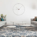 Modern living room with a large wall clock, coffee tables, and a patterned rug.