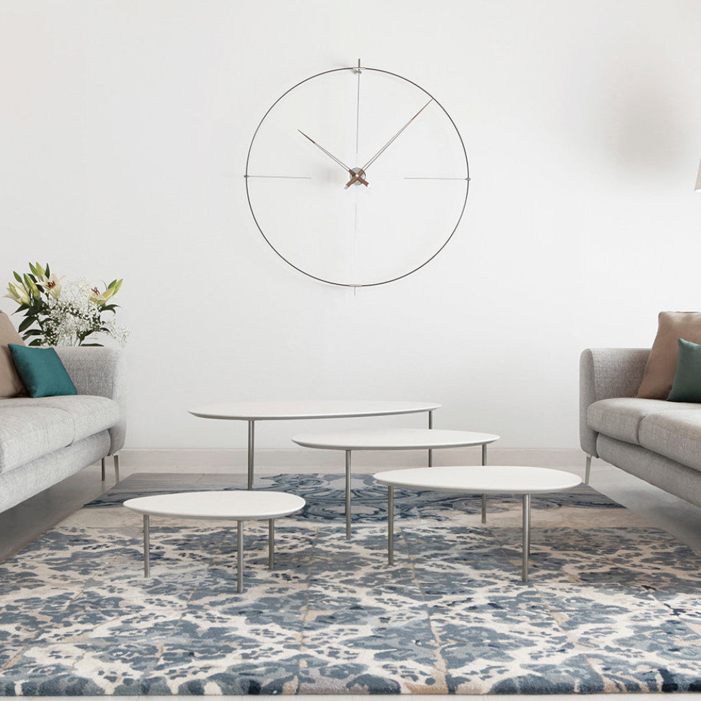 Modern living room with a large wall clock, coffee tables, and a patterned rug.