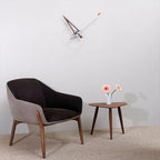 Modern chair and side table with a minimalistic wall clock in a room.