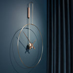 Modern wall clock with gold frame and bronze hands on a blue wall.