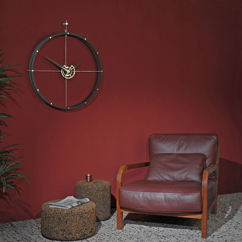 Brown leather armchair and ottomans against a red wall with a decorative clock.