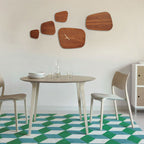 Dining room with a round table, chairs, and decorative wooden wall clocks.