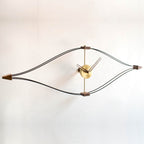 A Nomon handcrafted wall clock made of brass and wood with a creative eye shape, the Clock Nomon Look Mini Gold Walnut Arms MLON000N.
