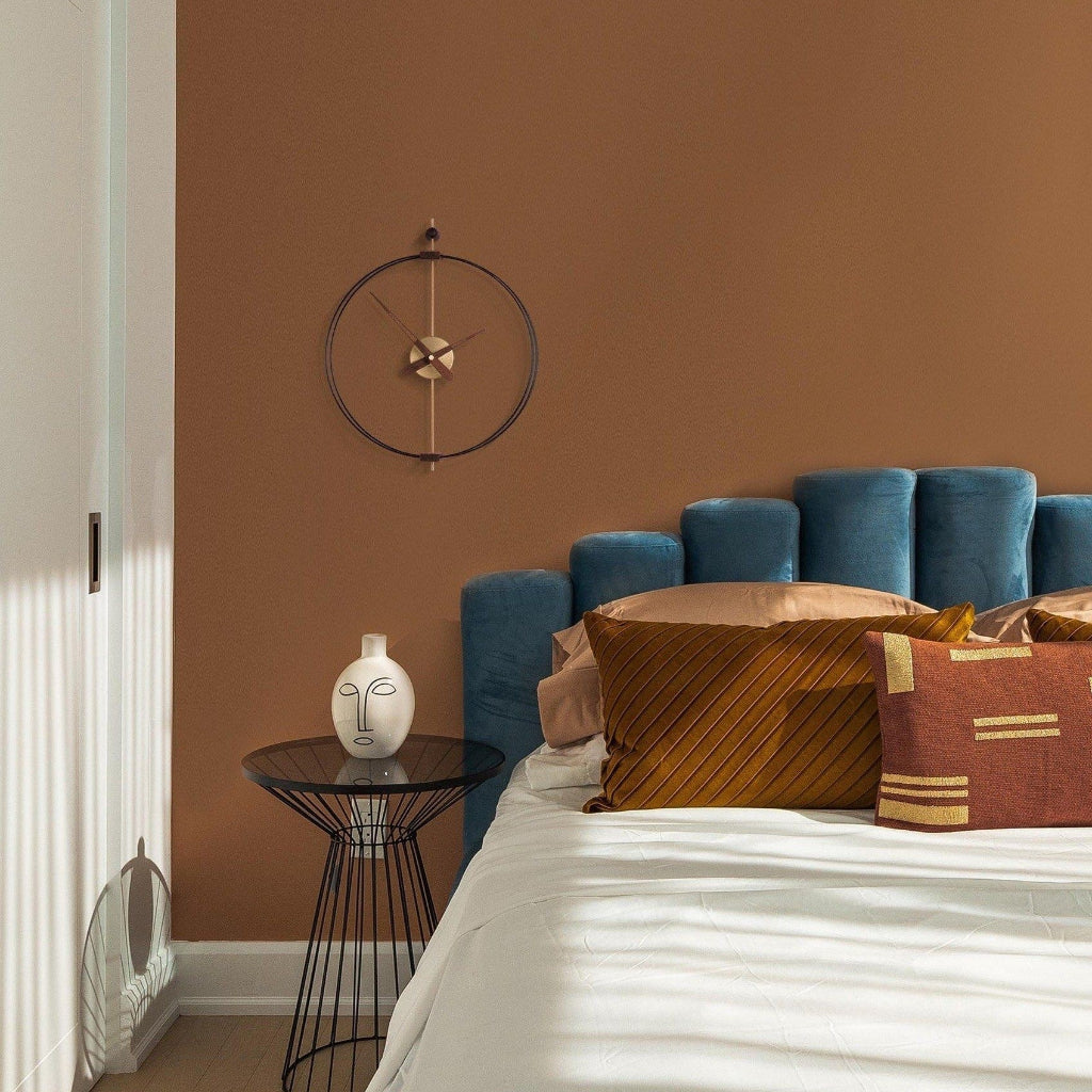 Bedroom with blue headboard, decorative pillows, and a wall clock.