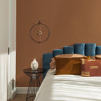 Bedroom with blue headboard, decorative pillows, and a wall clock.