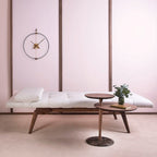 Modern interior with a bench, small round table, and decorative items against a pink wall.