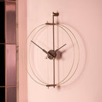 Decorative wall clock with gold and black design on a pink wall.