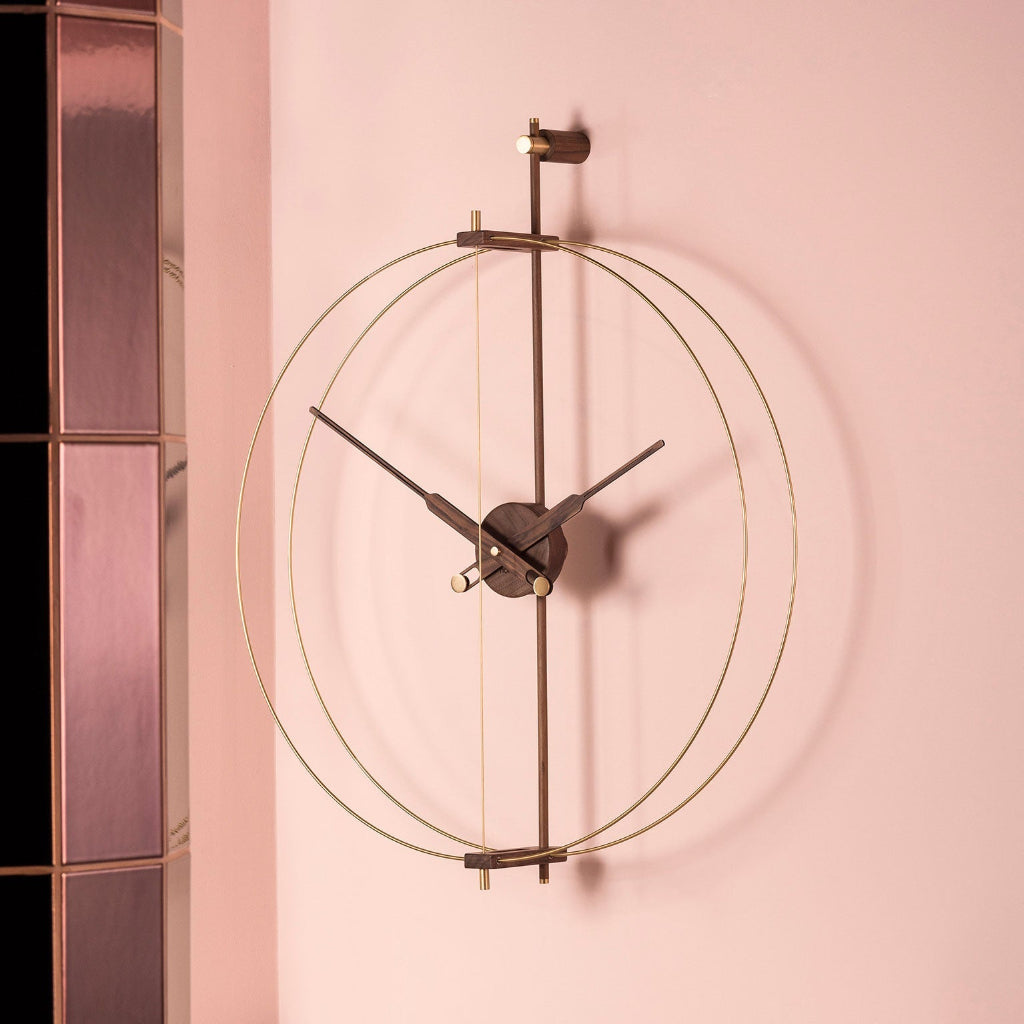 Decorative wall clock with gold and black design on a pink wall.