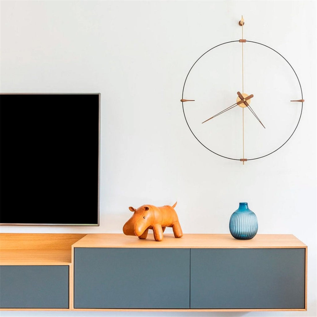 Modern living room with a television, decorative clock, and small sculptures on a wooden shelf.