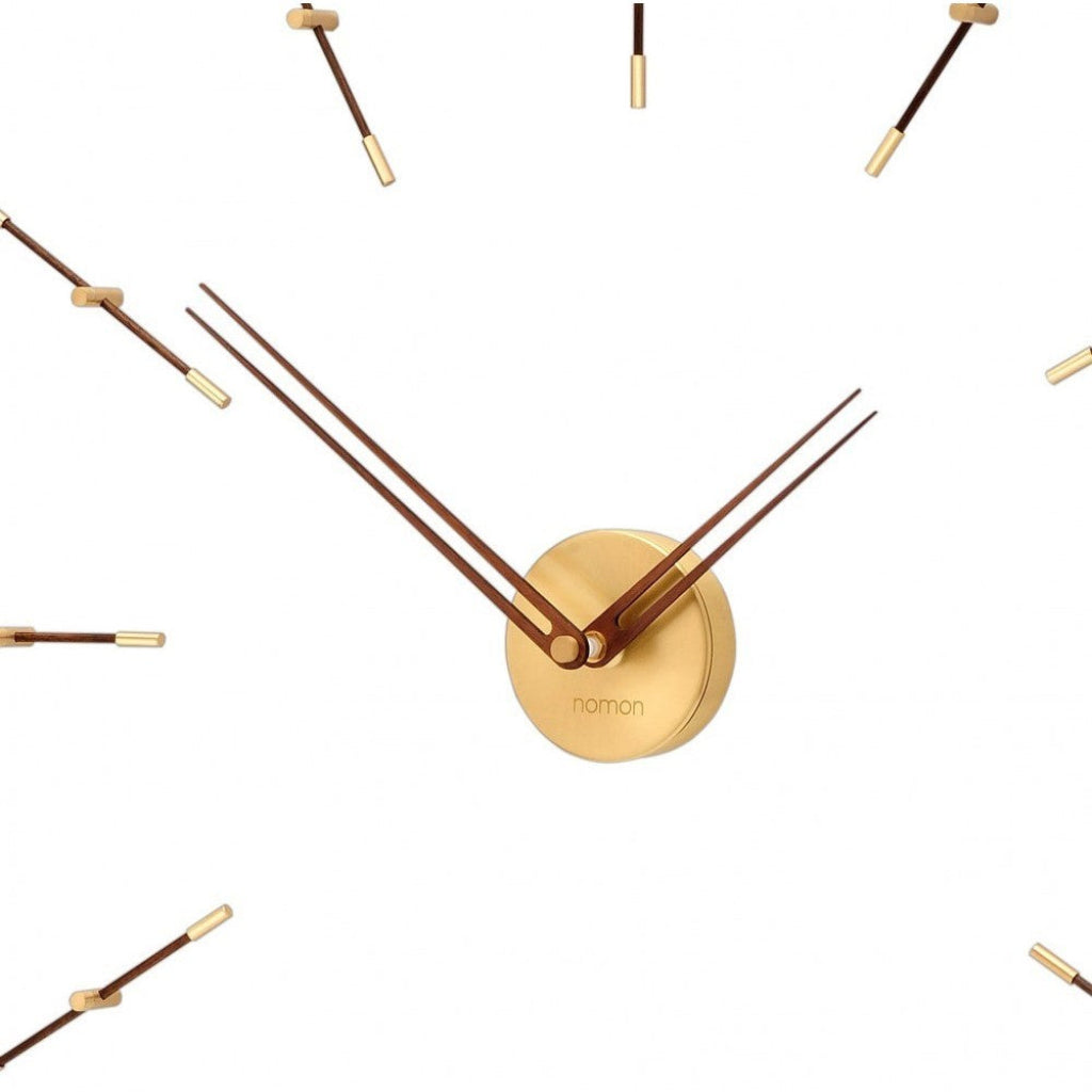 Gold wall clock with long thin hands on a white background