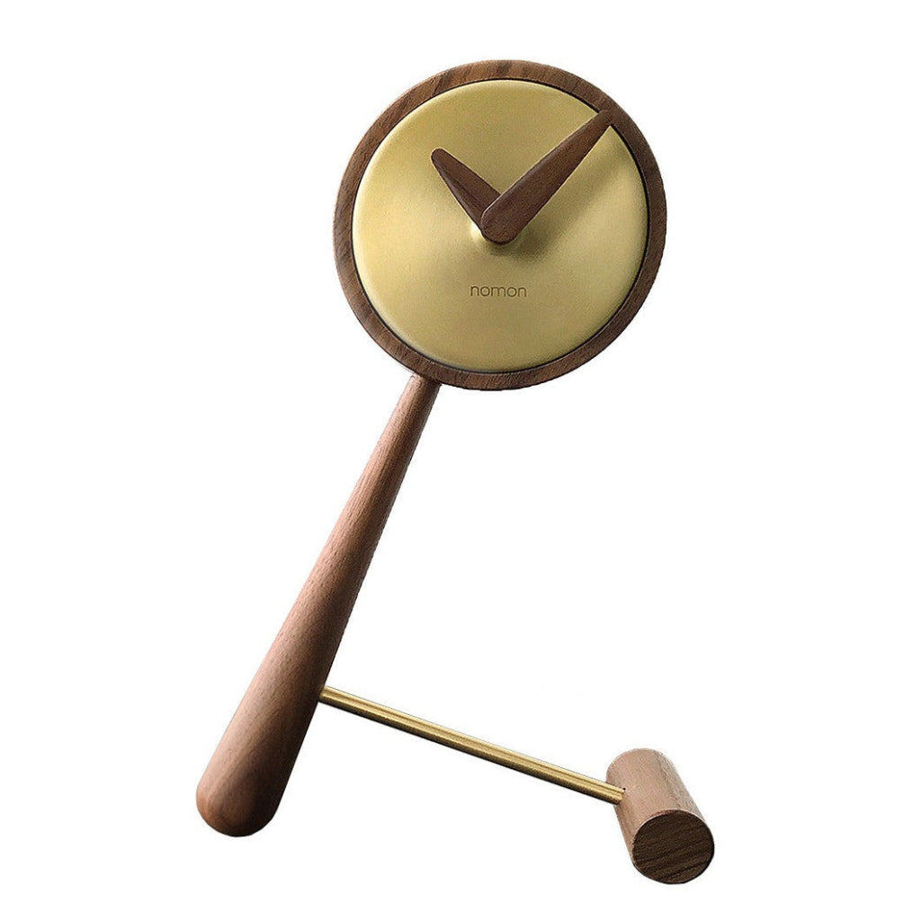 The Clock Nomon Mini Puntero G MPUNG is a high-end designer clock crafted from walnut wood, elegantly displayed on a wooden stand. available at Spacio retail stores in Mumbaii & Kolkata and online.