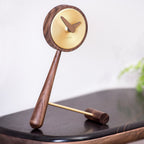 Wooden pendulum clock on a black surface with a blurred background
