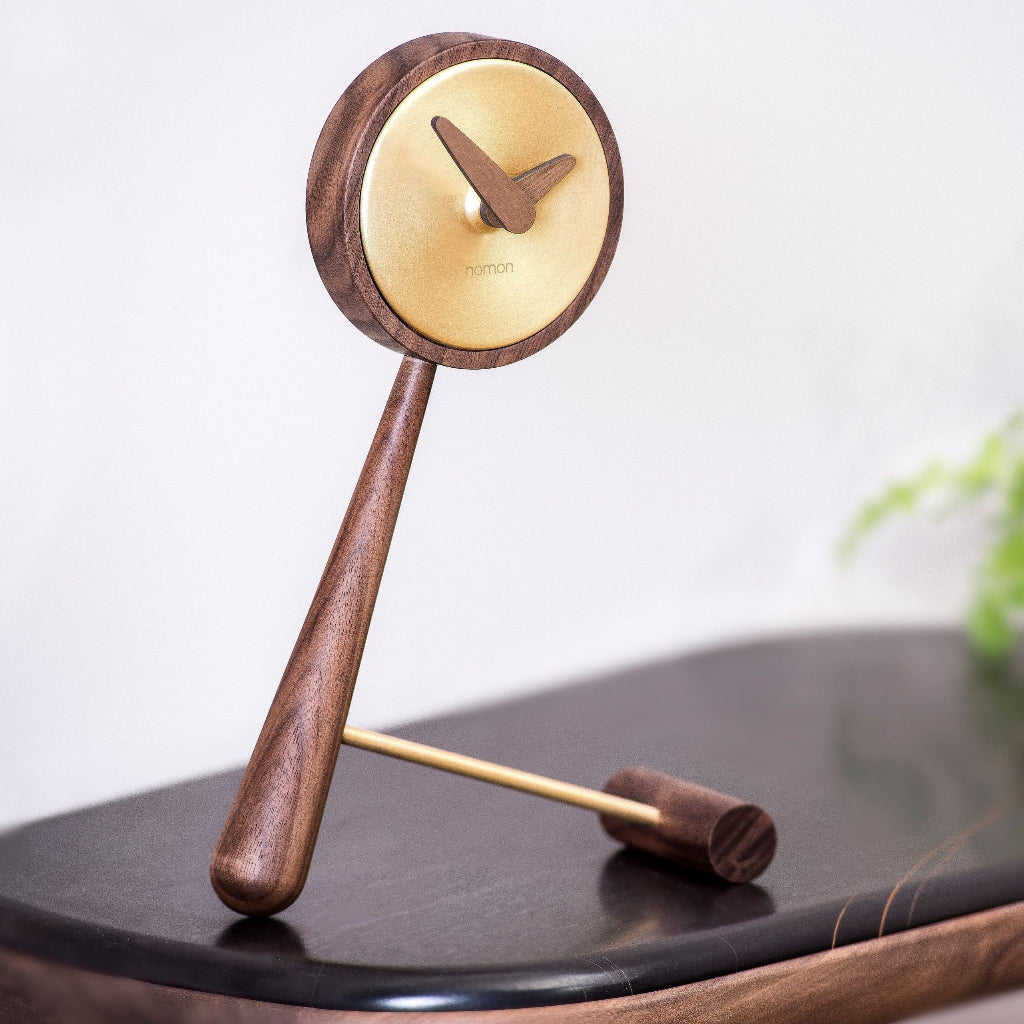 Wooden pendulum clock on a black surface with a blurred background