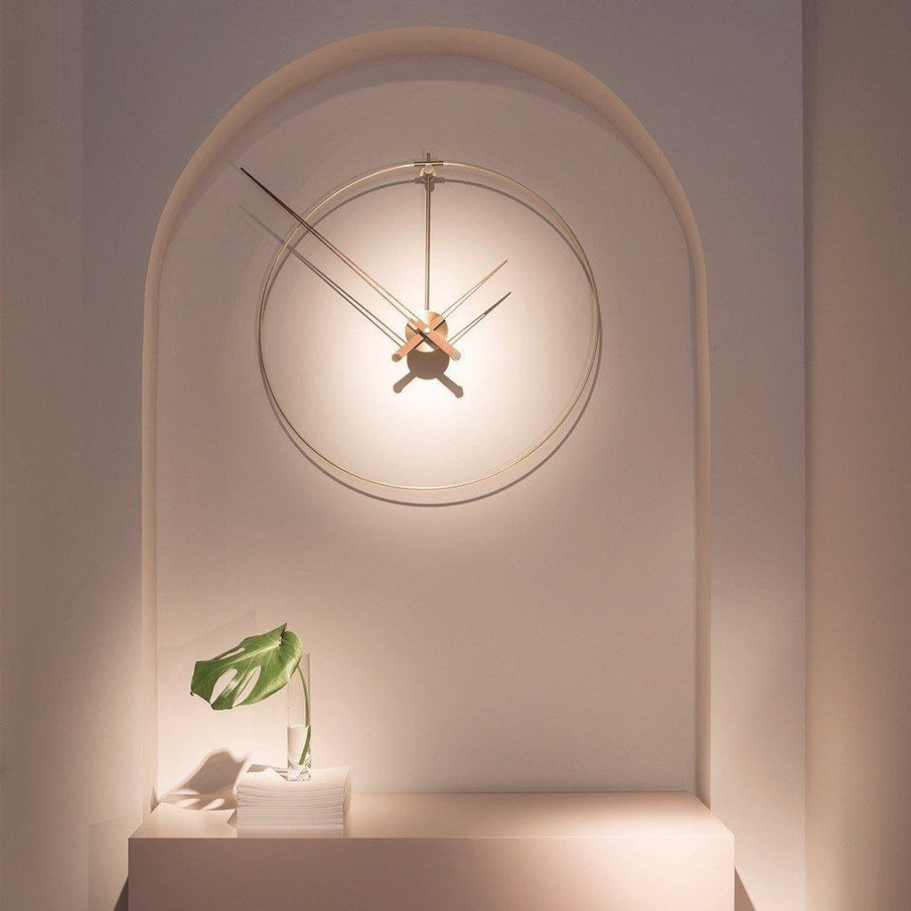Decorative wall clock on a wall with a plant and books below