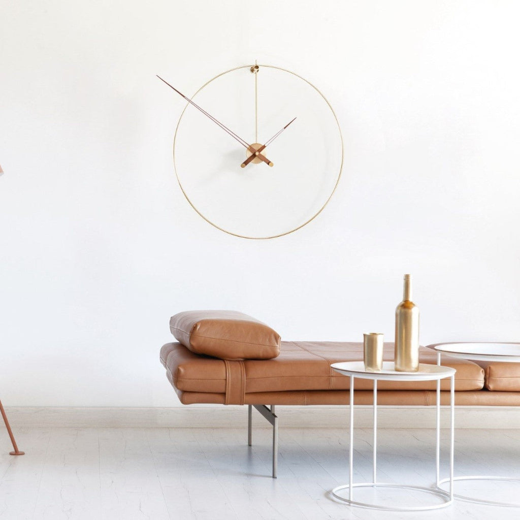 Modern living room with a leather sofa, round table, and gold wall clock.