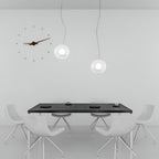 Modern dining area with a black table and white chairs under pendant lights.
