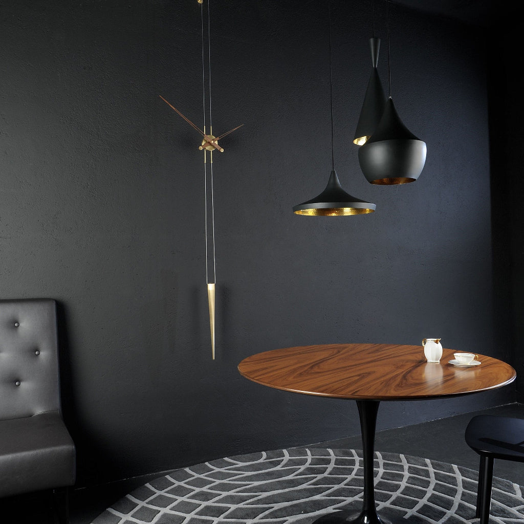 Modern interior with a wooden table, gray sofa, and hanging pendant lights against a dark wall.