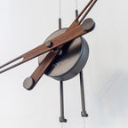 Close-up of a modern wall clock with wooden arms on a light background