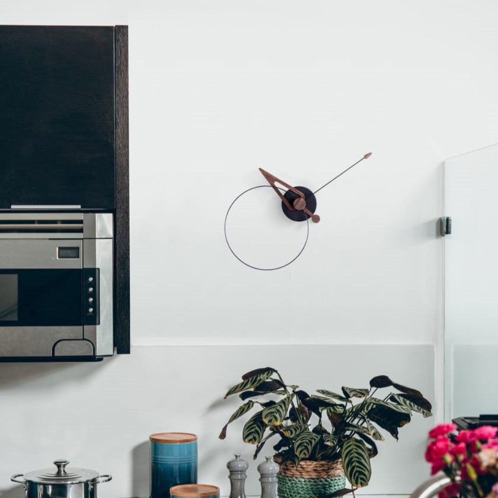 Modern kitchen with a wall clock, plant, and colorful flowers.