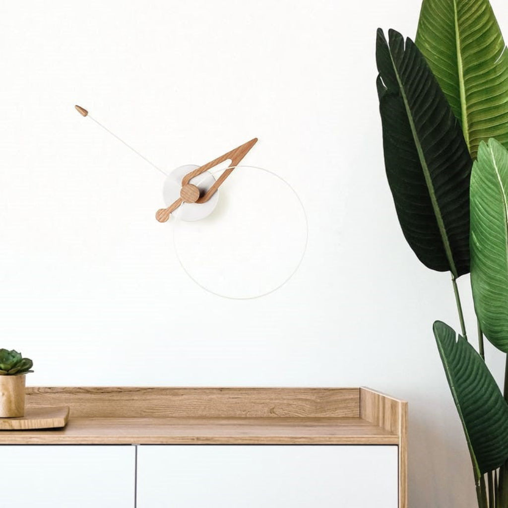 Wooden desk with a clock and plant against a white wall