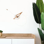 Wooden desk with a clock and plant against a white wall