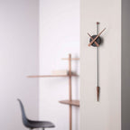Modern wall clock with long pendulum on a light gray wall
