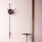 Modern wall clock with long pendulum on a light pink wall