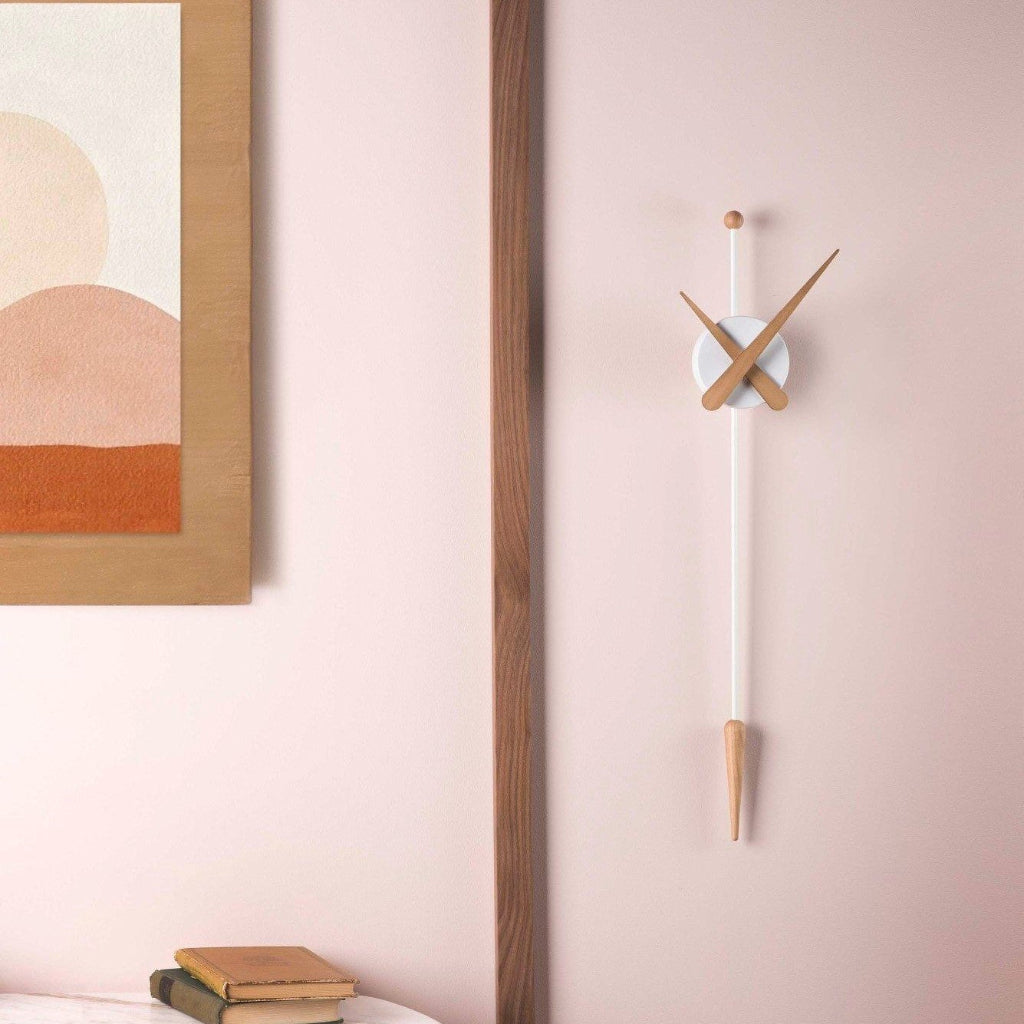 Wall clock with wooden accents on a pink wall next to abstract art