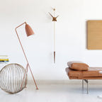 Modern interior with a floor lamp, wall light, and leather bench.