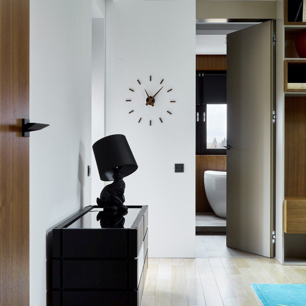 Modern interior with a black lamp and clock on a white wall.