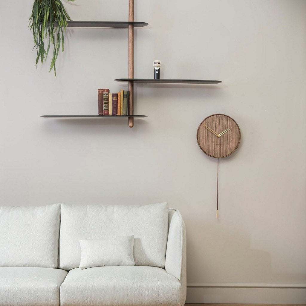 Wooden wall clock on a beige wall with shelves and a white sofa.