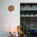 Wooden wall clock on a white wall with a modern interior setting.