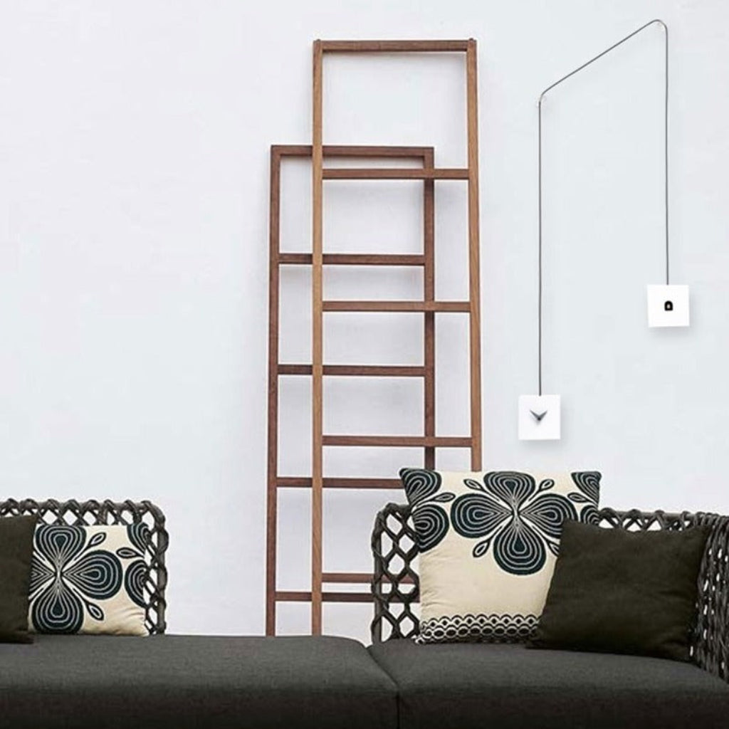 Wooden ladder against a white wall with decorative pillows on a sofa.