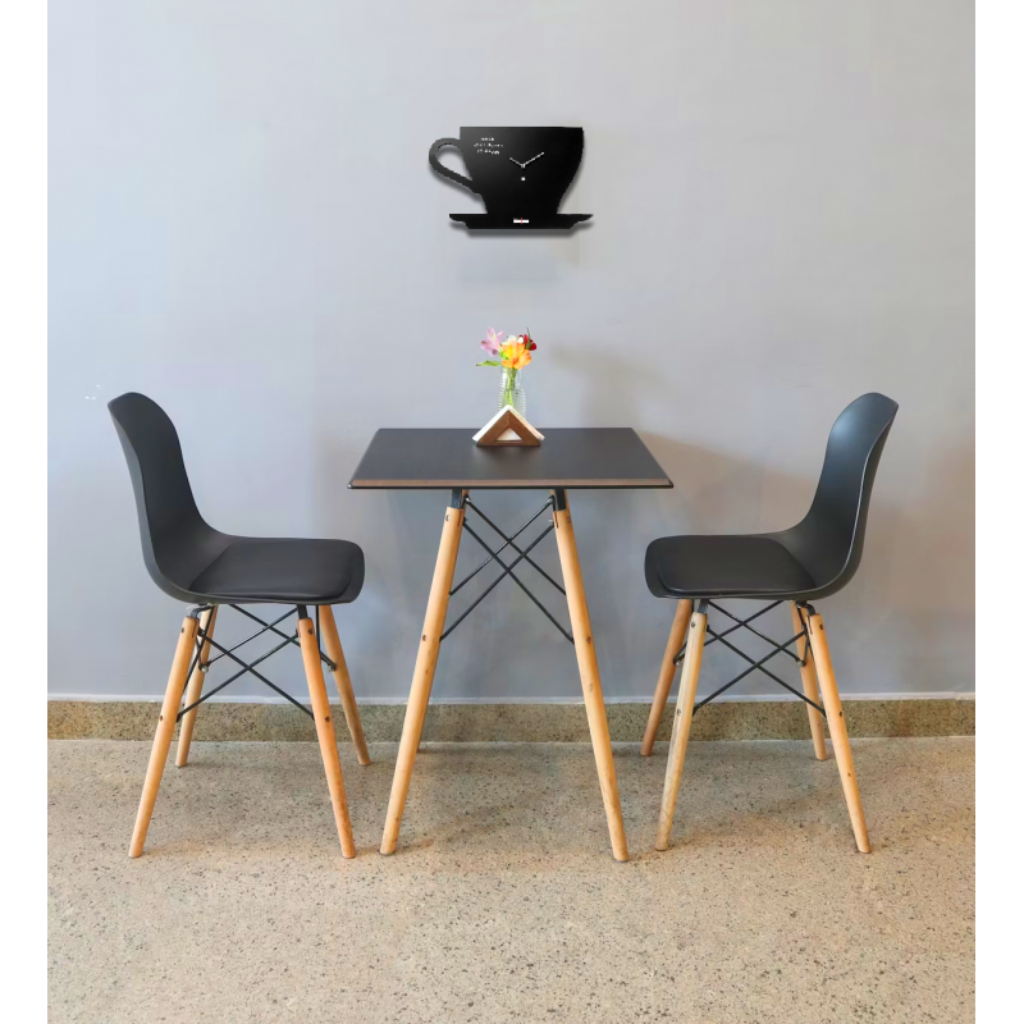 Small dining table with two black chairs against a light gray wall.