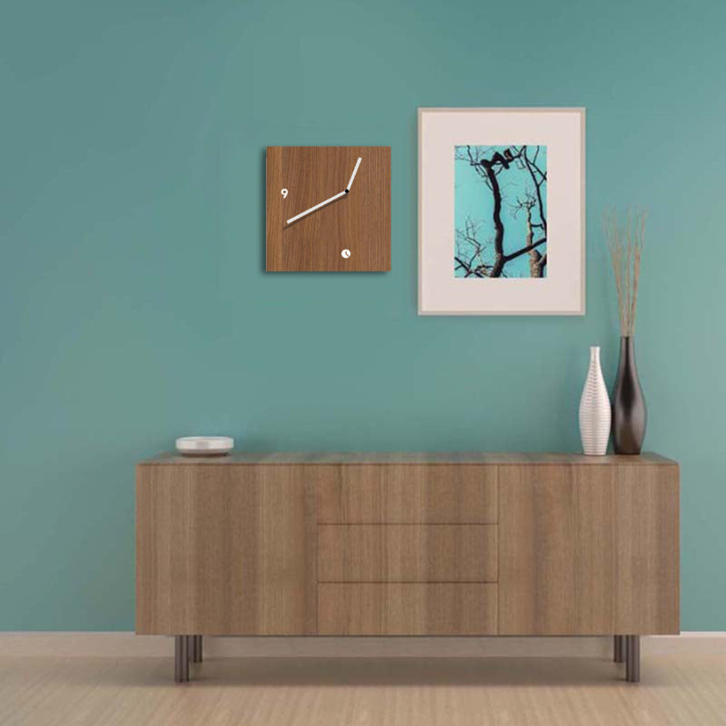Wooden sideboard against a teal wall with a clock and framed picture.